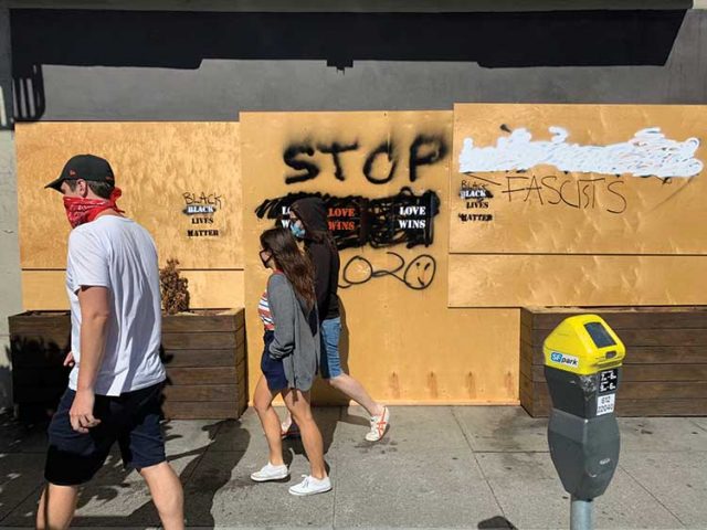Boarded storefronts become message boards on Polk Street.