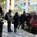 Drug dealers hand wads of cash to a man in an SUV while an Urban Alchemy ambassador watches.