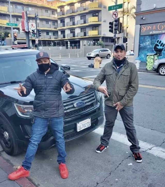 Drug dealers pose with a police cruiser.